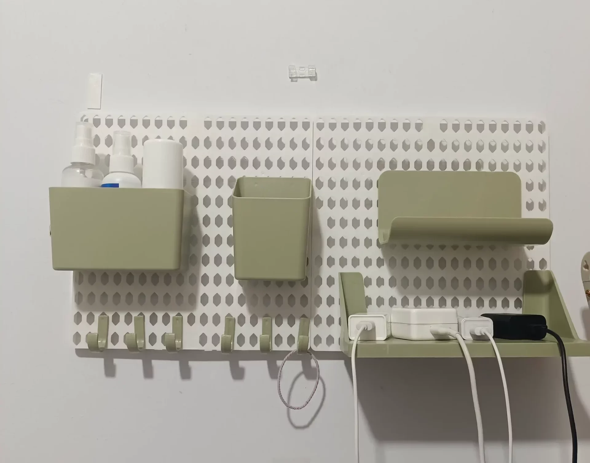 A white plastic pegboard on the wall with various of accessories