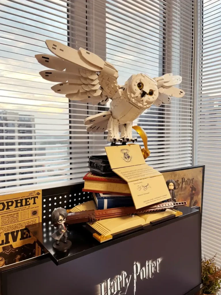 Harry Potter themed display with a large owl figure, collectible items, and a figurine of Harry Potter on a black shelf.