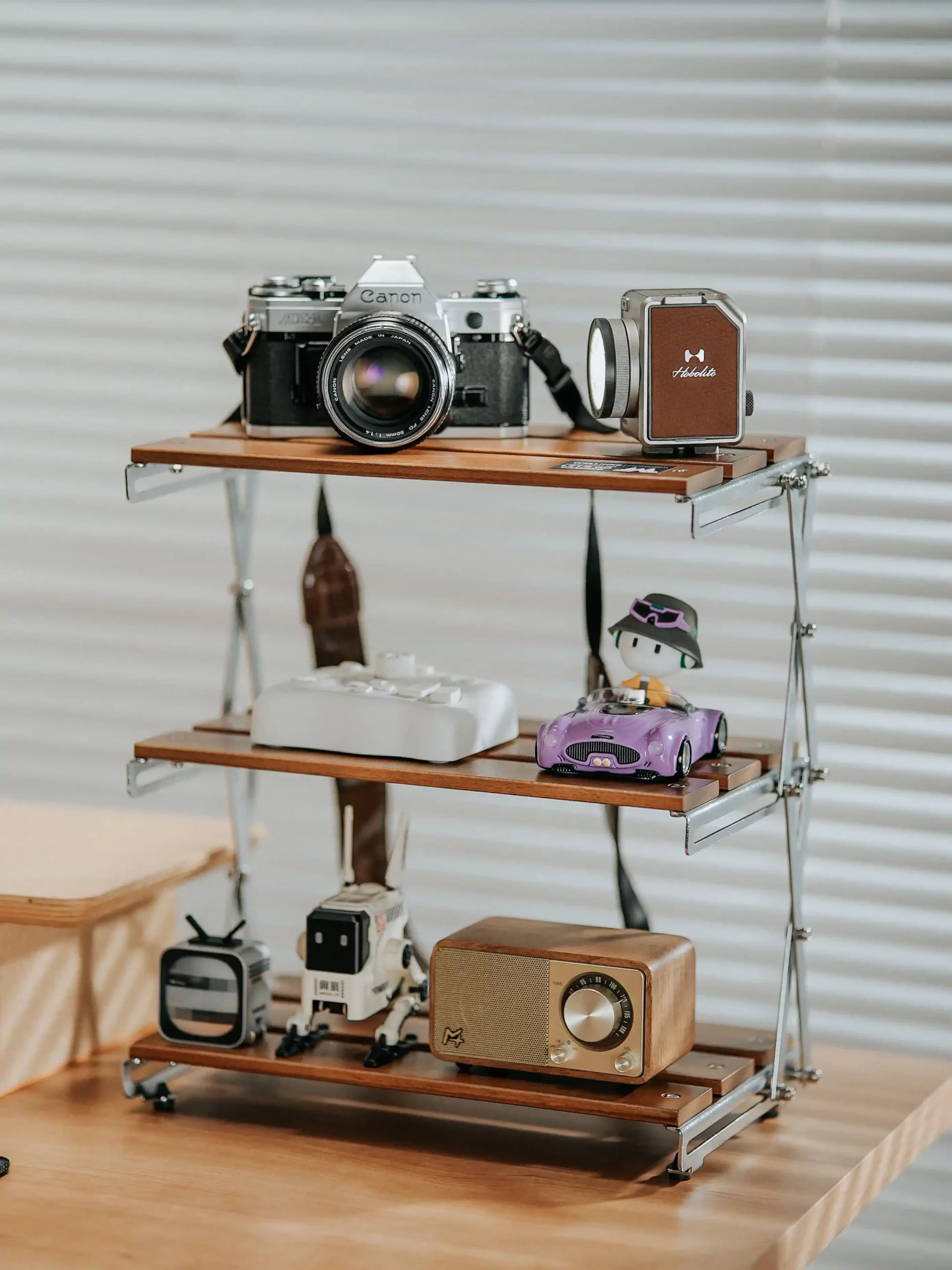 A display shelf with vintage cameras, a speaker, and assorted miniatures including a toy car and a small television.